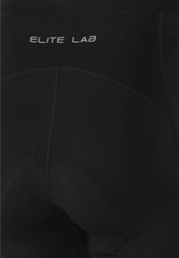 Zwarte fietsbroek van rekbaar materiaal, met ergonomische padding, zichtbare naden en de tekst "ELITE LAB" in het wit op de tailleband.