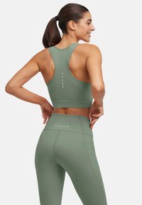 Zielony stanik sportowy z designem na plecy racerback i poziomą linią na plecach, w zestawie z dopasowanymi legginsami o wysokim stanie.