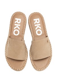 Sandales à glissière en daim beige avec une large bride, des bords cousus et une semelle intérieure tan. Présente un logo et un petit bouton décoratif en métal.