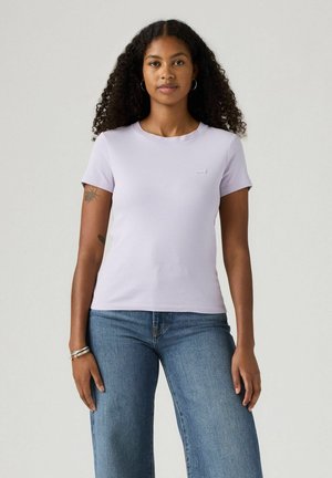 Lavendel färgad bomulls t-shirt med korta ärmar, rund halsringning och subtil logotypdetalj på framsidan. Kombinerad med ljusblå vida jeans.
