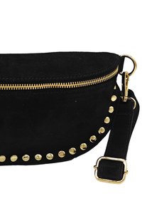 Sac à main en daim noir avec une forme courbée, fermeture éclair dorée et clous décoratifs le long du bord. Dispose d'une bandoulière en tissu ajustable.