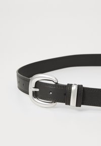 Cinturón de cuero negro con textura suave, equipado con una hebilla de metal plateado y una punta ajustable, diseñado con múltiples perforaciones.