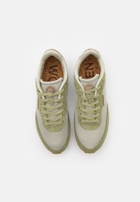 Zelené a béžové tenisky s materiály z síťoviny a semiše, kulaté otvory pro tkaničky, korková stélka a kulatý logo detail na jazyku.
