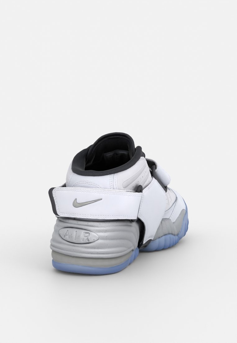 Zapatillas Nike con parte superior de cuero blanco y gris, interior negro y suela translúcida azul. Presentan una correa de Velcro y un detalle en relieve de "AIR".