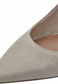 Chaussure à bout pointu en daim gris clair. Présente un décolleté bas et une doublure intérieure lisse. Coutures discrètes le long du bord. Semelle plate.