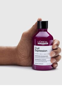 Krullen Expressie shampoo in een paarse kunststof fles van 300 ml met een zwarte dop, voorzien van een wit etiket met productdetails en ingrediënten.