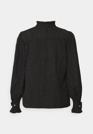 Blouse noire à manches longues avec un col montant à volants, tissu texturé et poignets boutonnés avec détails à volants.