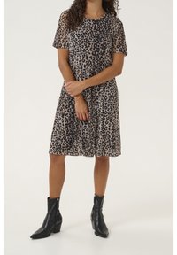 Leopard print dress with short sleeves, semi-sheer fabric, flared shape, and knee-length hem. Paired with black ankle boots.