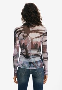 Long-sleeve top made of lightweight fabric features a floral and abstract pattern in shades of pink and blue, with a fitted design and seamless back.