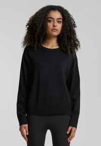 Zwart gebreid sweater met een ronde halslijn, lange mouwen en ribbelzoom. Zachte textuur met een ontspannen pasvorm.