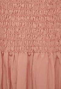 Abito rosa con un corpino smockato texturizzato e una gonna morbida e fluida. Il tessuto sembra leggero e leggermente trasparente, con dettagli di arricciatura intricati.