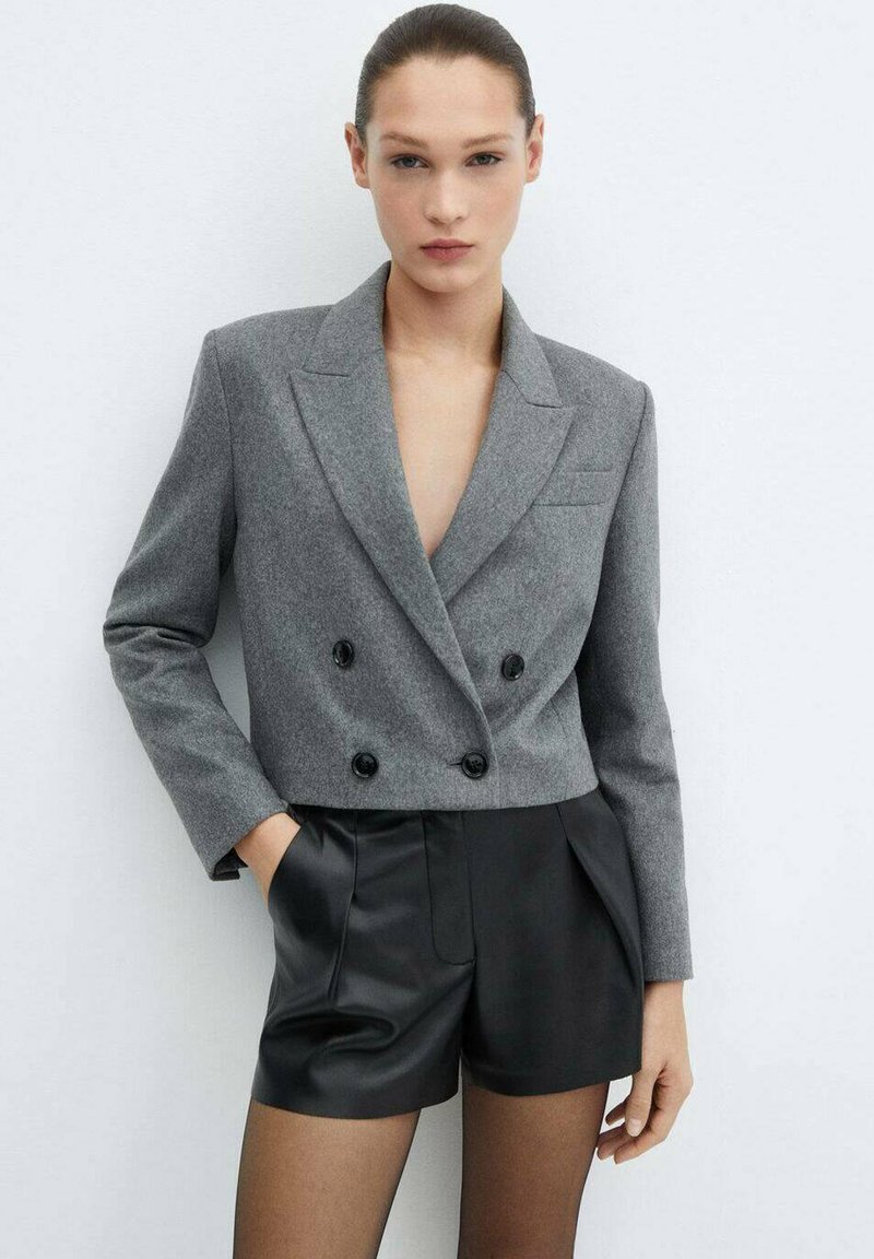 Grijze dubbelgeknoopte cropped blazer in een gestructureerde stof met zwarte knopen, notch-ook en een slanke, aansluitende pasvorm; gecombineerd met zwarte leren short.
