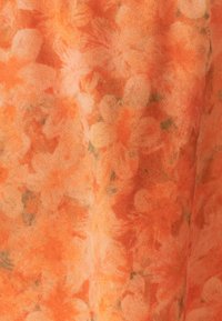 Bloemenstof met een zachte textuur op een oranje achtergrond, met een patroon van licht en donkeroranje bloemen en subtiele groene accenten.