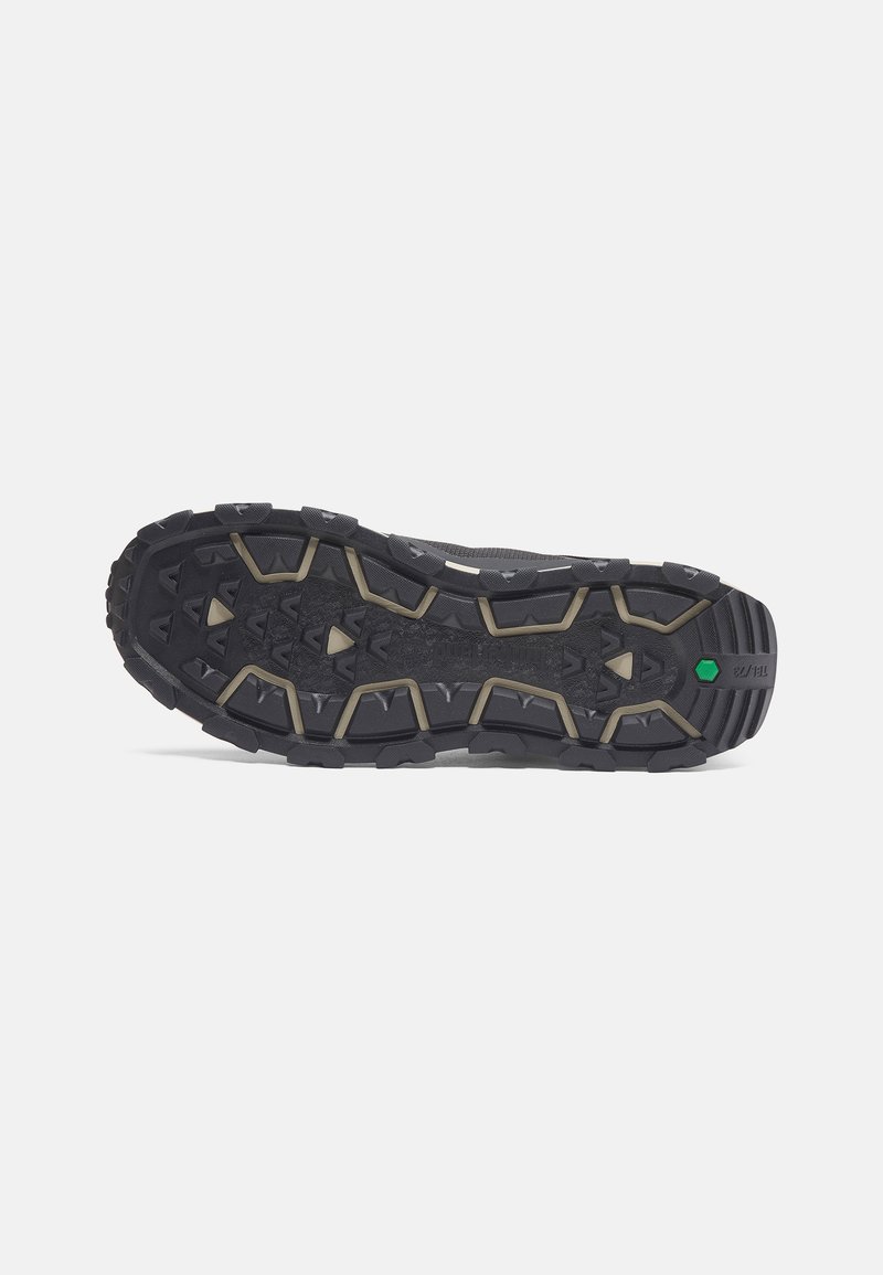 Zwarte robuuste sneakersool met agressief profiel, voorzien van verhoogde geometrische patronen en een groene accent detail voor grip.