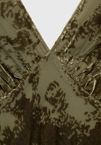 Vestido de terciopelo verde oliva con diseño de cuello en V. La tela texturizada presenta un sutil patrón floral y detalles fruncidos en los hombros.
