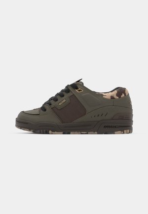 Green leather sneaker with dark brown accents, black laces, padded collar, and camo-patterned lining. Features textured sides and durable sole.