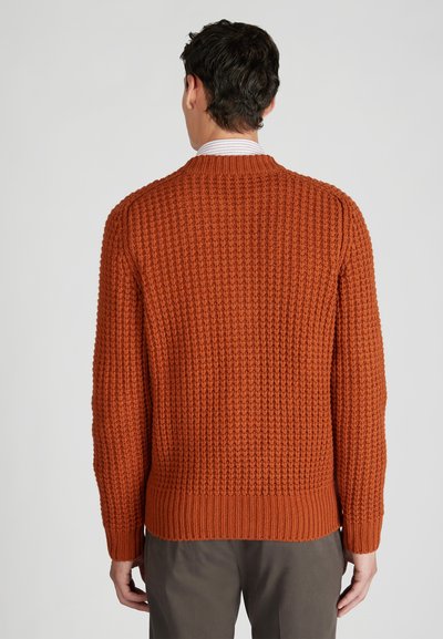Sweter z dzianiny w teksturowanym, spalonym pomarańczowym materiale; ma długie rękawy i ściągacz na dole, widok z tyłu ukazuje dopasowany krój.