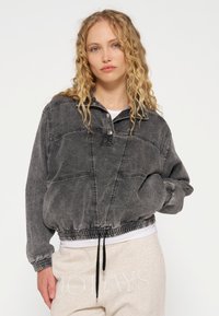 Pullover in denim grigio con mezze bottoni, orlo e polsini elasticizzati, con cuciture a contrasto e una vestibilità morbida.