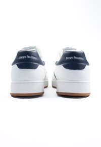 Fehér bőr sportcipők tengerészkék díszítéssel, párnázott bokarészes, gumitalppal és "Sergio Tacchini" márkázással a saroknál.