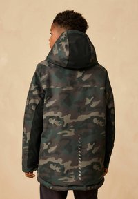 Camouflage parka with a hood; primarily green, brown, and black patterns; water-resistant material; long sleeves; straight hem with striped detail.