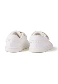 Zapatillas blancas con una textura suave, que presentan un borde ondulado y una correa de Velcro. Suela de goma de perfil bajo para comodidad y estabilidad.