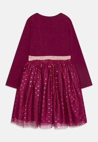 Bordowa sukienka z długimi rękawami, błyszczącym złotym pasem i warstwową spódnicą z tiulu, na której znajdują się małe srebrne wzory w kształcie serc.