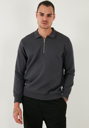 Dark grey quarter-zip pullover made of smooth cotton blend fabric. Features a collar and ribbed cuffs, with a relaxed fit and minimal design.