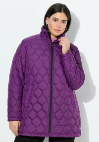 Fialová prošívaná puffer bunda s vysokým límcem, předním zipem a bočními kapsami. Má vystouplý diamantový vzor a hladkou, lesklou texturu.