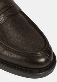 Braune Leder-slipper mit strukturiertem Finish, runder Zehenpartie und dekorativer Steppnaht. Schwarze Gummisohle für Halt und Haltbarkeit.