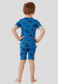 Blaues Baumwoll-Pyjama-Set mit kurzen Ärmeln und Shorts, verziert mit bunten Cartoon-Tiermustern, Rückansicht, mit nackten Füßen.