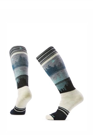 Paar kniekousen met blauw, zwart en wit boslandschapmotief en zwarte tenen en hielen op een witte achtergrond.