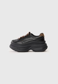 Black leather sneaker with a thick sole, featuring a rounded shape, brown braided laces, and a leopard print accent on the heel.