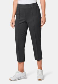 Zwarte, cropped broeken met een elastische tailleband en zijnaad. Gecombineerd met witte sneakers met een gestructureerde bovenkant en rubberen zool.