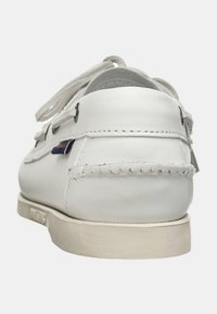 Scarpa da barca in pelle bianca con tomaia testurizzata, punta rotonda e suola in gomma bianca. Presenta cuciture decorative e un accento scuro vicino al tallone.