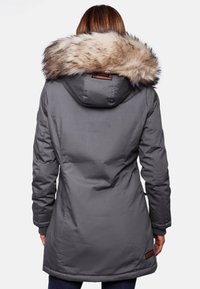 Grå parka-jakke med hætte af kunstpels, der har et tætsiddende design, lange ærmer og et læderlogo-patch nær kanten.