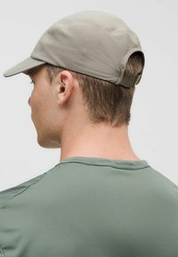 Jasnoszara czapka z wygiętym daszkiem, teksturowana tkanina i tylna regulacja, noszona z zieloną koszulą z krótkim rękawem. Prosty i funkcjonalny design.