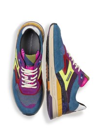 Zapatillas coloridas con una mezcla de materiales en azul, morado, rojo y amarillo. Parte superior de malla texturizada y detalles con patrones. Diseño de suela gruesa.