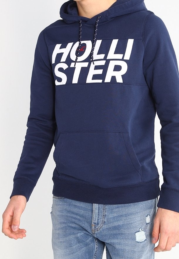 Sudadera azul marino con un gran logo blanco de "HOLLISTER", capucha con cordones, bolsillo tipo canguro en la parte frontal y puños y dobladillo acanalados.