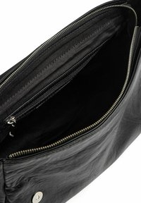 Interno di una borsa in pelle nera con tasca con cerniera, texture elegante, due scomparti e dettagli in metallo argentato. Foderatura in tessuto morbido.
