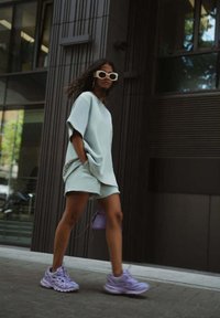  Lichtblauwe oversized sweatshirt en bijpassende shorts, gecombineerd met lavendel sneakers. Toegankelijk gemaakt met witte zonnebril en een kleine paarse handtas.