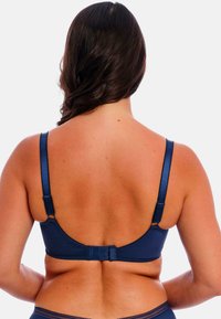 Navy blauwe beha van zacht materiaal met verstelbare bandjes en een haak-en-oogsluiting. Heeft een eenvoudig ontwerp met minimale versieringen.