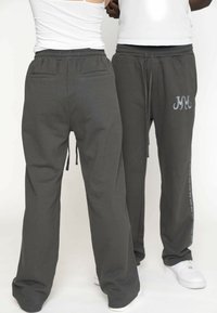 Donkergrijze sweatpants met een relaxte pasvorm, een tailleband met trekkoord, achterzakken en zijdetails in lichtgrijs. Ontworpen voor comfort en bewegingsvrijheid.