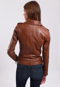 Brown leather jacket with a fitted design, wide lapels, and zippered sleeves. Smooth texture and seam detailing on the back.