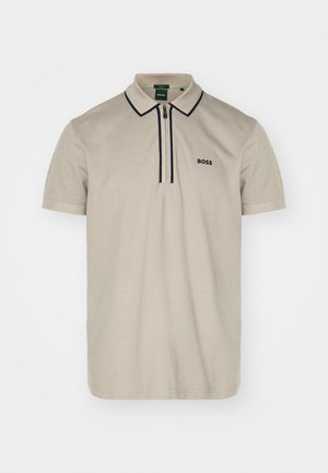 Polo en coton beige clair, avec une fermeture éclair et un bord contrastant foncé, arborant un discret logo "BOSS" sur la poitrine gauche.