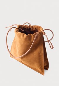 Sac à main en daim marron doux avec cordon de serrage, longues bandoulières en cuir et forme triangulaire sur fond blanc.
