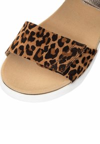 Sandal s leopardím potiskem, měkkým suédovým páskem, béžovou stélkou a bílou podrážkou. Navrženo pro pohodlí a snadné nošení.