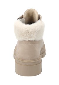 Beige suède enkellaars met een zachte witte bontkraag, ronde vorm en stevige rubberen zool. Verstelbare zijgesp detail.