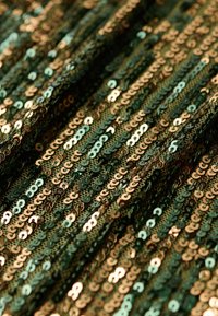 Groen en gouden paillettenstof met een patroon van overlappende cirkelvormige pailletten, met een gladde textuur en glanzend reflecterend oppervlak.