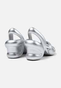 Silver platform sandals with smooth metallic finish, sculpted curved heels, and open-back design featuring multiple straps across the front.