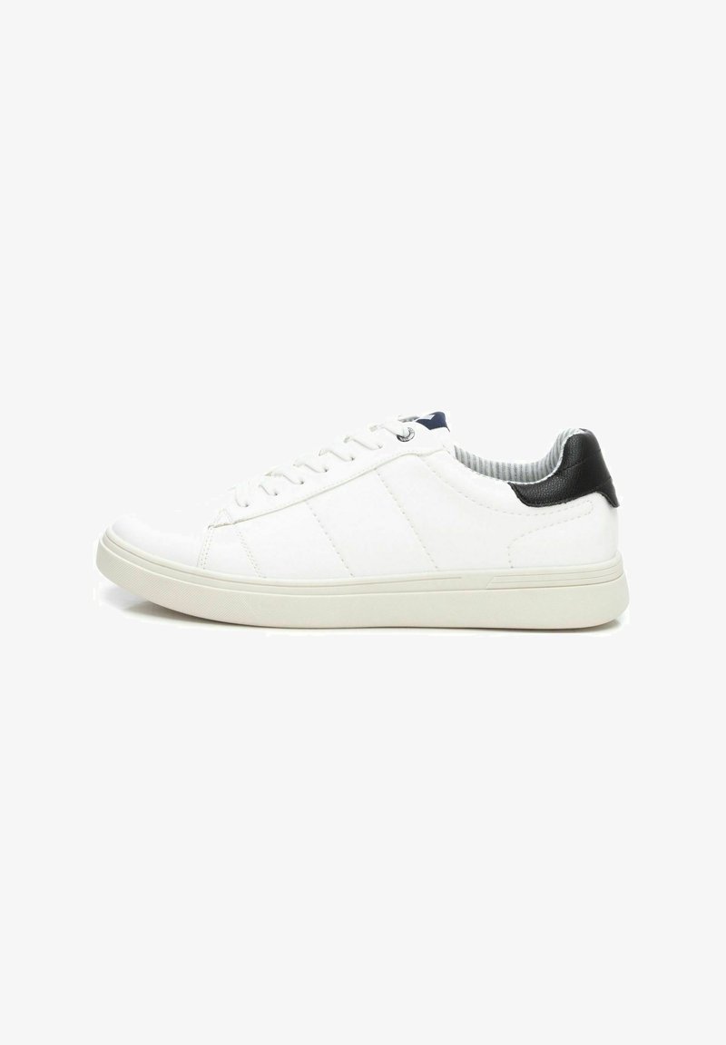Zapatilla blanca con cordones, con una parte superior de cuero suave, tres rayas cosidas, cuello acolchado y una tapa de talón negra en contraste.
